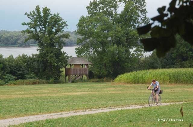 Blick auf den Turm aus größerer Distanz mit dem Chiemsee im Hintergrund.