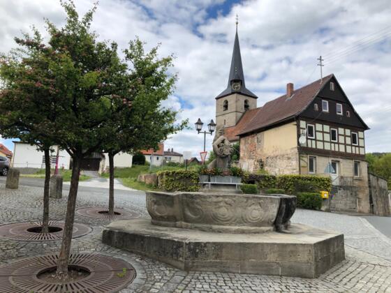 Blick über den Jungfer-Kättl-Brunnen zur Dreieinigkeitskirche in Weißenbrunn