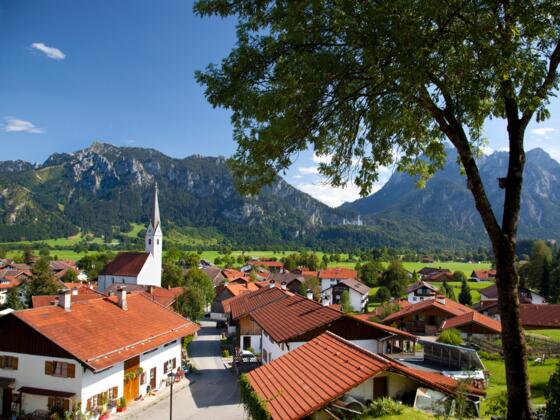 Blick vom Schwangauer Kurpark zum Schloss Neuschwanstein und Ammergebirge