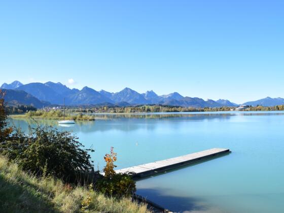 Forggensee mit Steg und Berge im Hintergrund