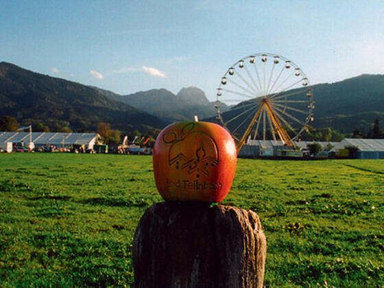 Blick auf das Gelände des Feilnbacher Apfelmarktes mit Riesenrad und traumhafter Bergkulisse im Hintergrund.