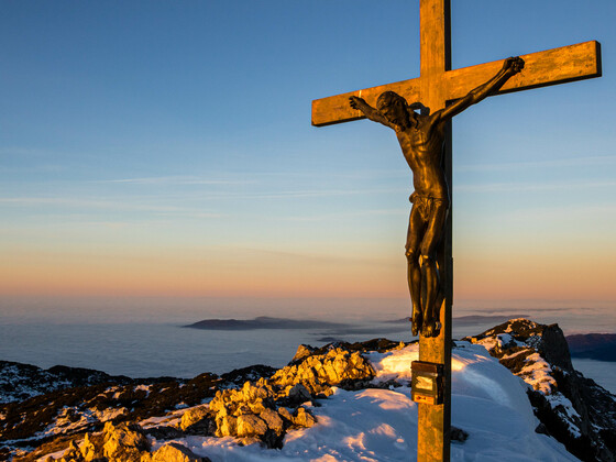 Das Gipfelkreuz auf dem Berchtesgadener Hochthron im Abendlicht über dem Nebelmeer.