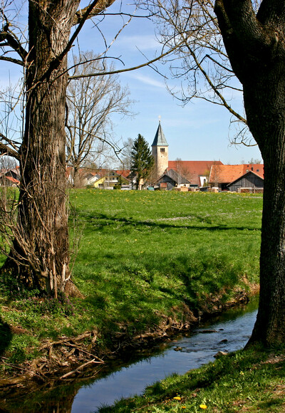 Die Peitnach mit der Kirche St. Michael von Peiting im Hintergrund