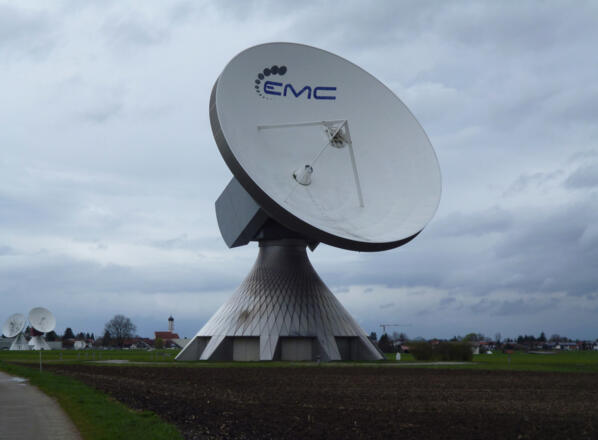 Hinter den riesigen Parabolantennen der Erdfunkstelle wirkt die Raistinger Pfarrkirche St. Remigius vergleichsweise winzig.