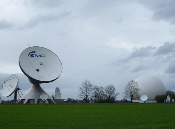 Die übergroßen Antennen der Erdfunkstelle und das Radom vor den Häusern von Raisting.