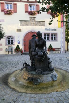 Der Brunnen auf dem Merkendorfer Marktplatz zeigt eine Frau und einen Mann mit Körben voller Kraut.