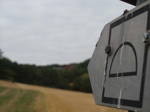 Dieses Zeichen mit einem stilisierten Hügelgrab weist den Weg.