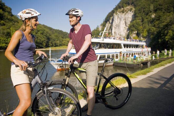 Radfahrer vor einem Schiff beim Kloster Weltenburg - Fahrräder können auf den Schiffen mitgenommen werden.