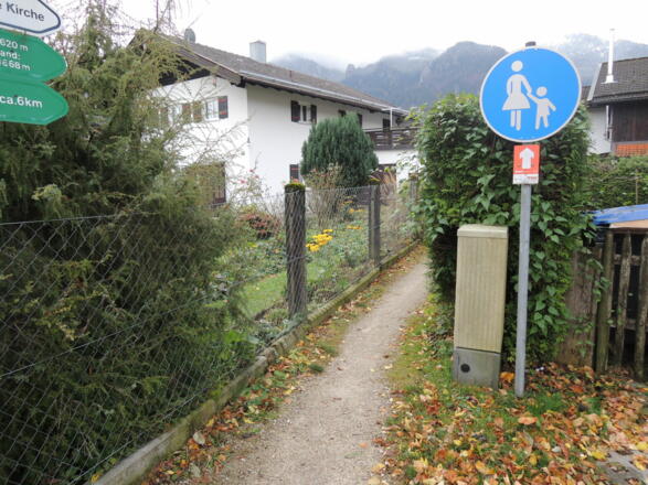 Nach Querung der Straße geht es auf dem schmalen Fußweg weiter.