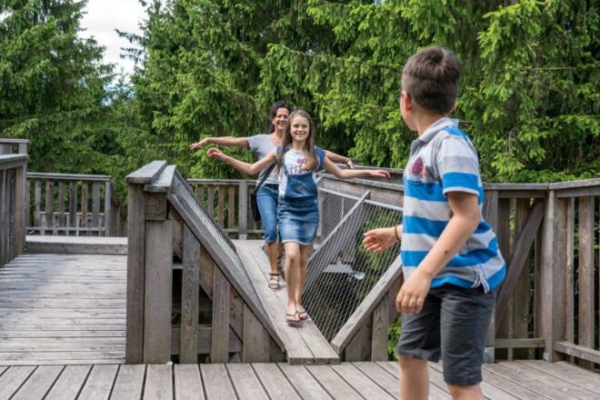 Familien balanciert über Holzsteg