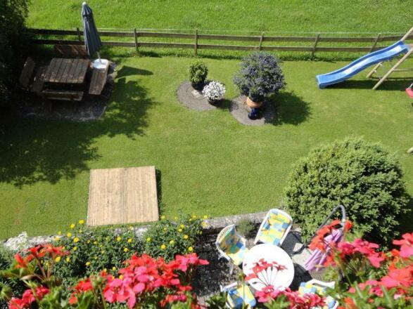 Blick vom Balkon auf die Liegewiese mit Spielplatz