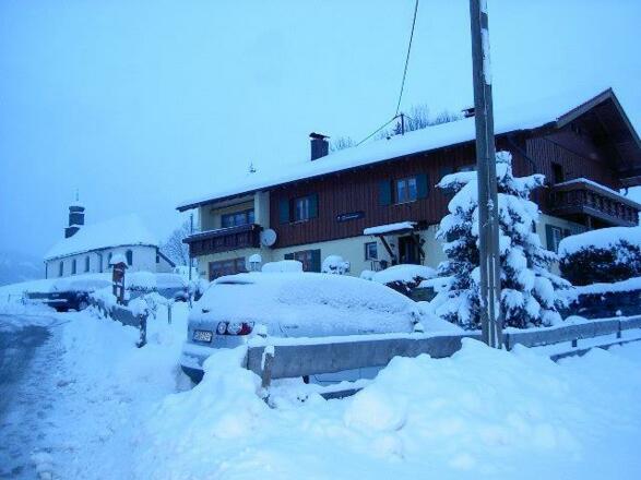 Verschneites haus mit Kapelle im