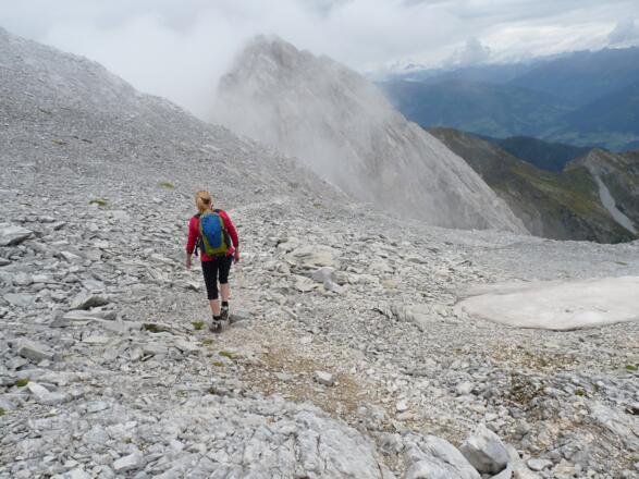 Über das weite Schotterkar steuern wir den westseitigen Abstieg ab. Hinten ragt die Kl. Kinigat empor.