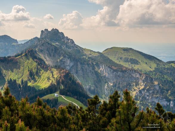 Blick von der Hochplatte runter auf die Piesenhausener Hochalm und darüber das Kampenwandmassiv.