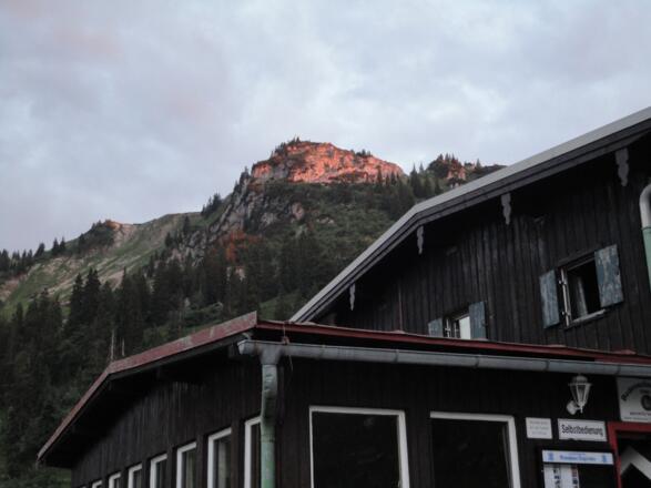 Über dem Bodenschneidhaus leuchtet der Gipfelaufbau der Bodenschneid in der Abendsonne