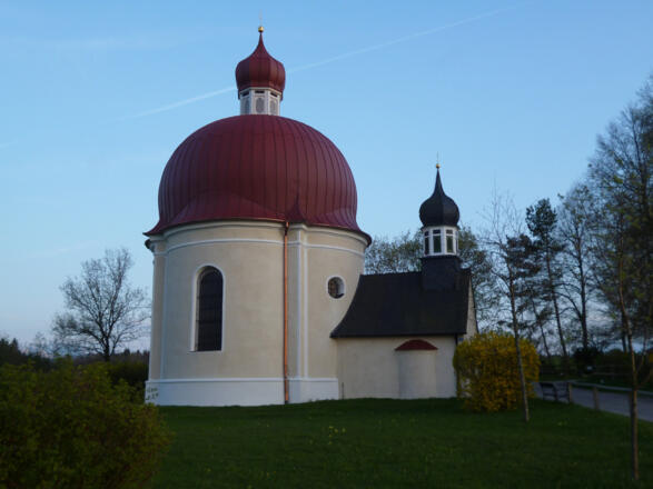 Der originelle Rundbau der Heuwinklkapelle mit dem vorgelagerten Glockenturm thront auf einem Hügel oberhalb von Iffeldorf.
