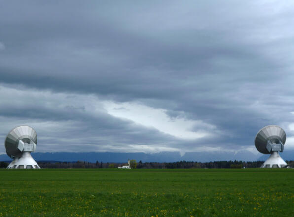 Blick zwischen den riesigen Antennen der Erdfunkstelle hindurch auf die Kapelle St. Johann.