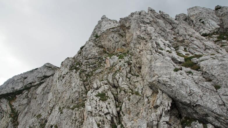 Vom Steinmann (im Ausstieg aus der unteren Rinne) überblickt man den weiteren Wegverlauf (Bildmitte) durch die Verschneidung