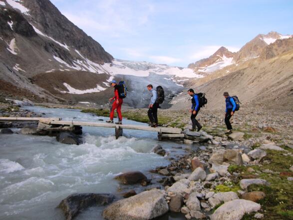 Die provisorische Holzbrücke über den Alpeiner Bach führt uns in wegloses Gelände. Hinten der Alpeiner Ferner und die Wildgratspitzen. 