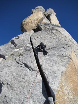 Von diesem kleinen Absatz (links steckt ein Schlaghaken) klettert man links des Risses weiter (5+).