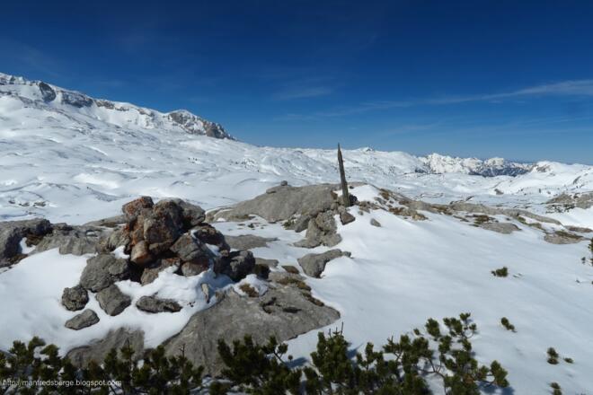 Ein Steinmann und eine Holzstange zieren den Gipfel
