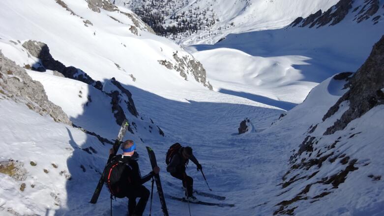 In der anfangs sehr schmalen Rinne seitlich abrutschen oder die Skier ein paar Meter hinunter tragen.