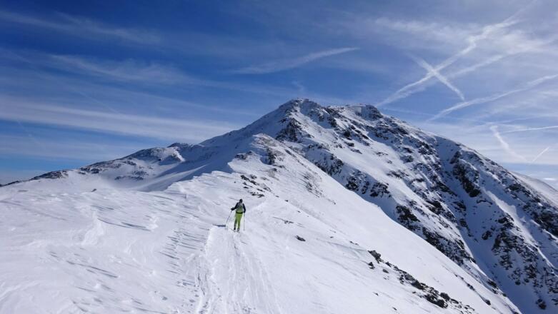 Der Rücken wird allmählich zum Grat. Gut erkennbar ist der vom Nordgipfel steil abfallende Nordhang. Am Fuße dieses Hanges quert man waagrecht nach links.