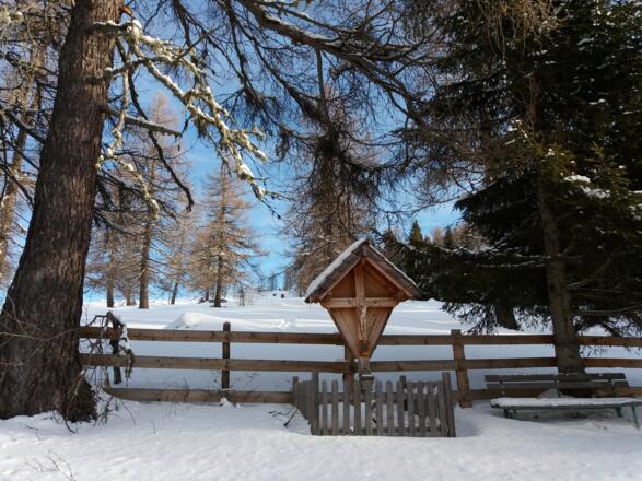 Eingefriedetes hölzernes Marterl oberhalb vom Spielplatz.