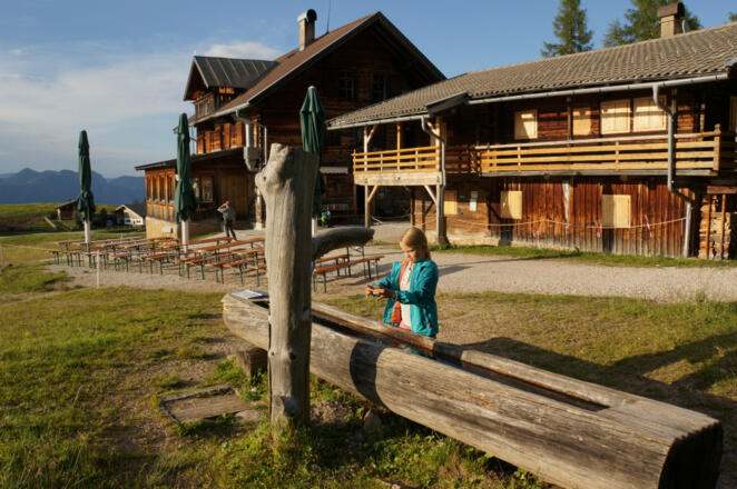 Kind vor der Holzalm am Brunnen