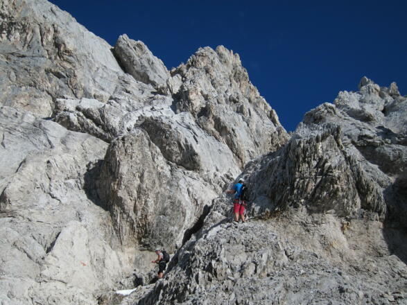Willkommene Abkühlung durch letzte Reste Herbstschnee. Die Rinne nach rechts oben vermittelt den Weiterweg.