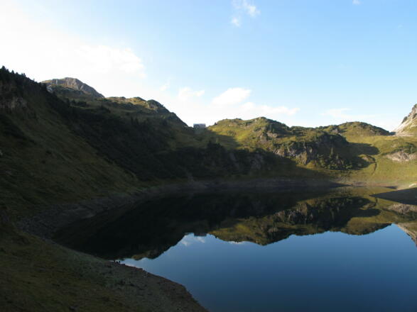 Morgenstimmung am Formarinsee mit der darüber liegenden Freiburger Hütte