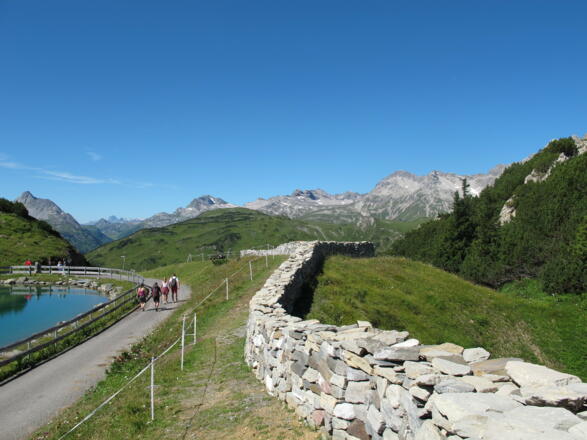 Lecher Mauer am Kriegersattel, die vom Künstler Daniel Nikolaus Kocher gestaltet wurde; auf den Steinen der Mauer sind die Lecher Bürger verewigt.